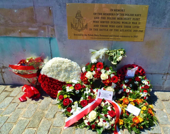 a pile of flowers with red and white ribbon around them