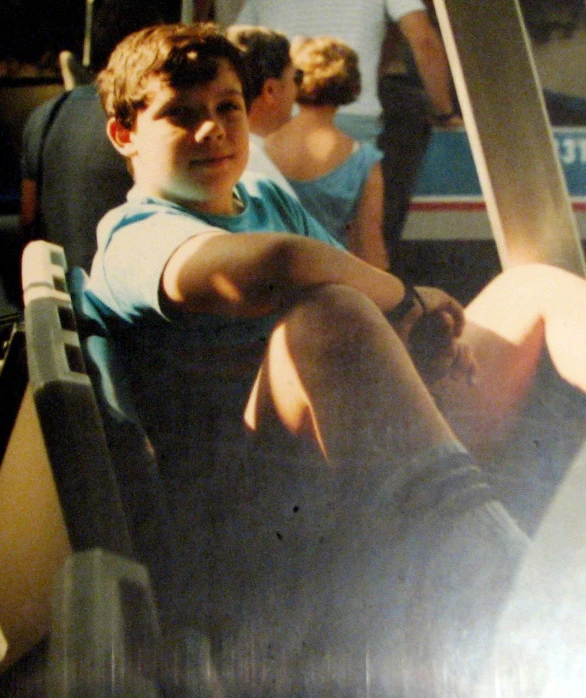 a boy sits on a bus with one foot up