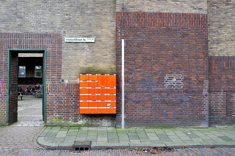 there is a small orange box that is next to the brick wall