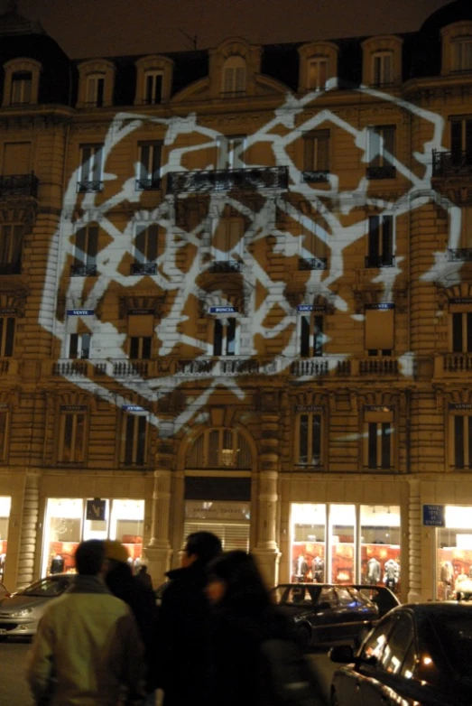 a group of people walk in front of a building with a digital art on the side