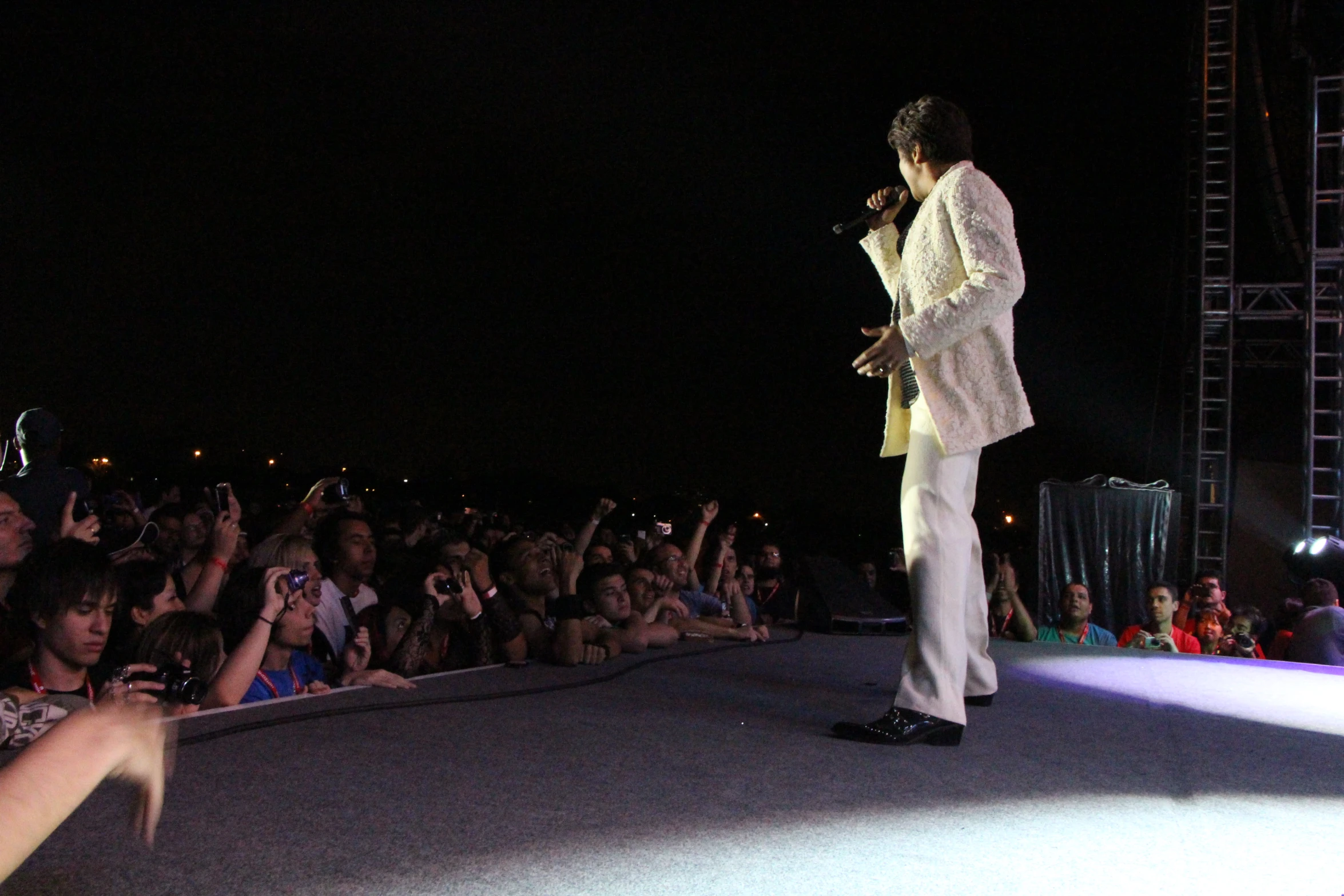 a man with white suit is standing in front of a group of people