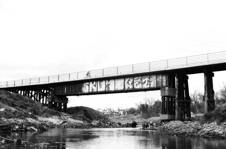 an old bridge with graffiti under it on the side of a hill