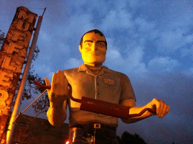 a guy standing in front of a large statue with a clock on top