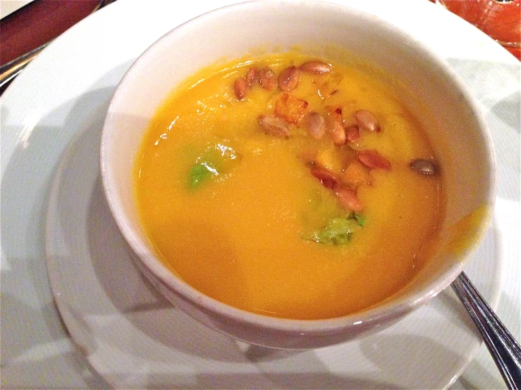 a bowl of carrot soup sitting on top of a plate