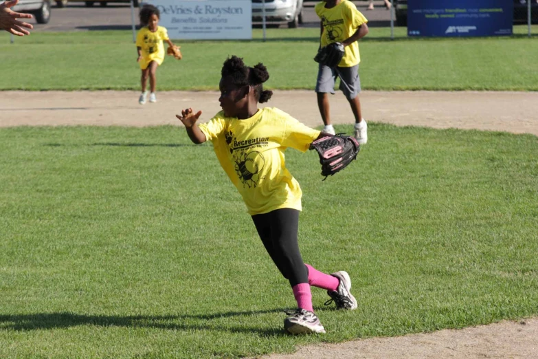 a little girl in yellow runs to catch a ball