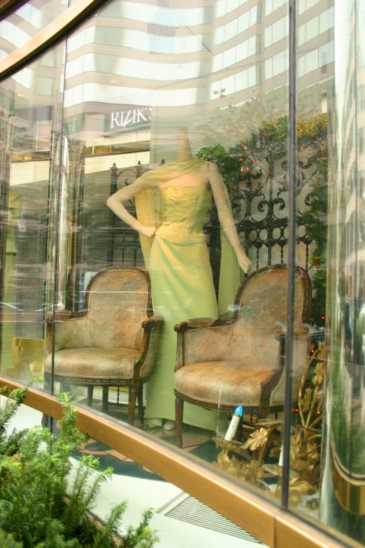 the mannequin in the window is in front of an old chair