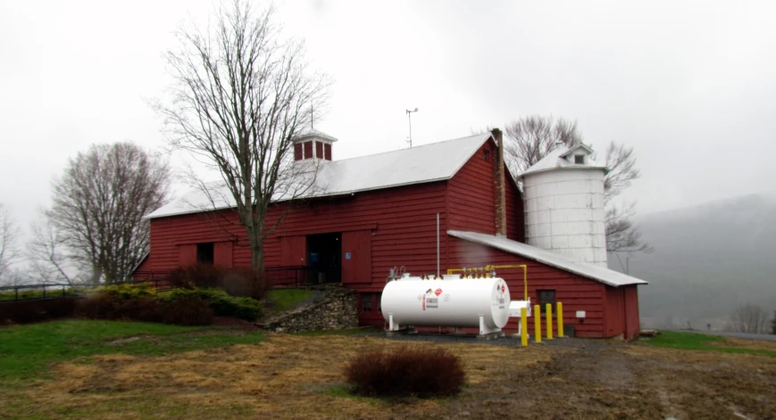 a red barn with a white silo and trees