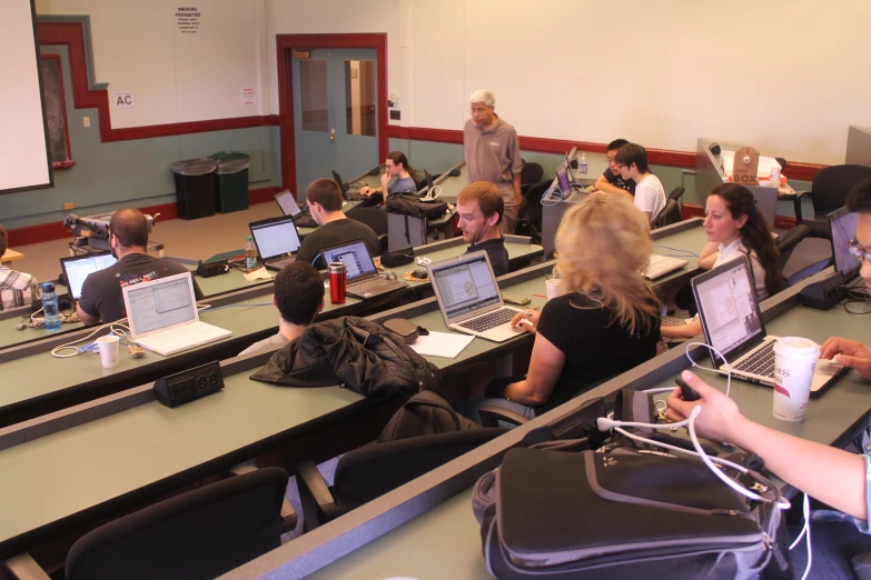 many people at tables with laptops and computers on them