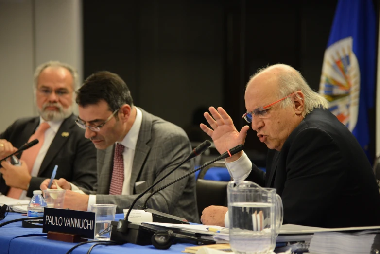 a few men sitting at a table while they listen