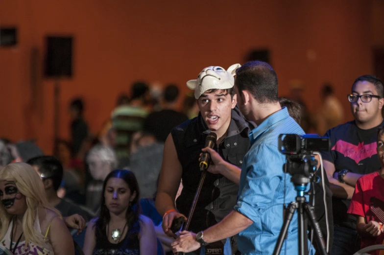 two men talk while a crowd of people hold their cameras