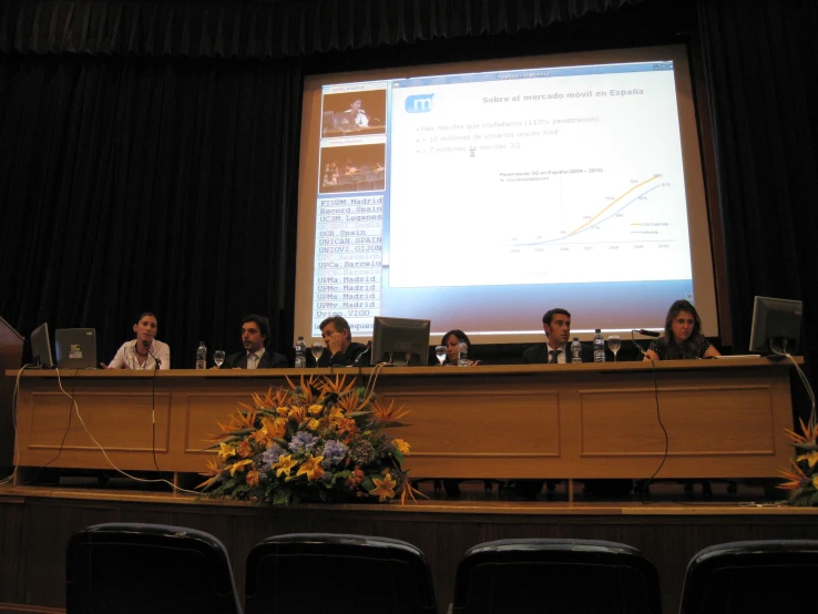 people sitting at a table with laptops in front of them