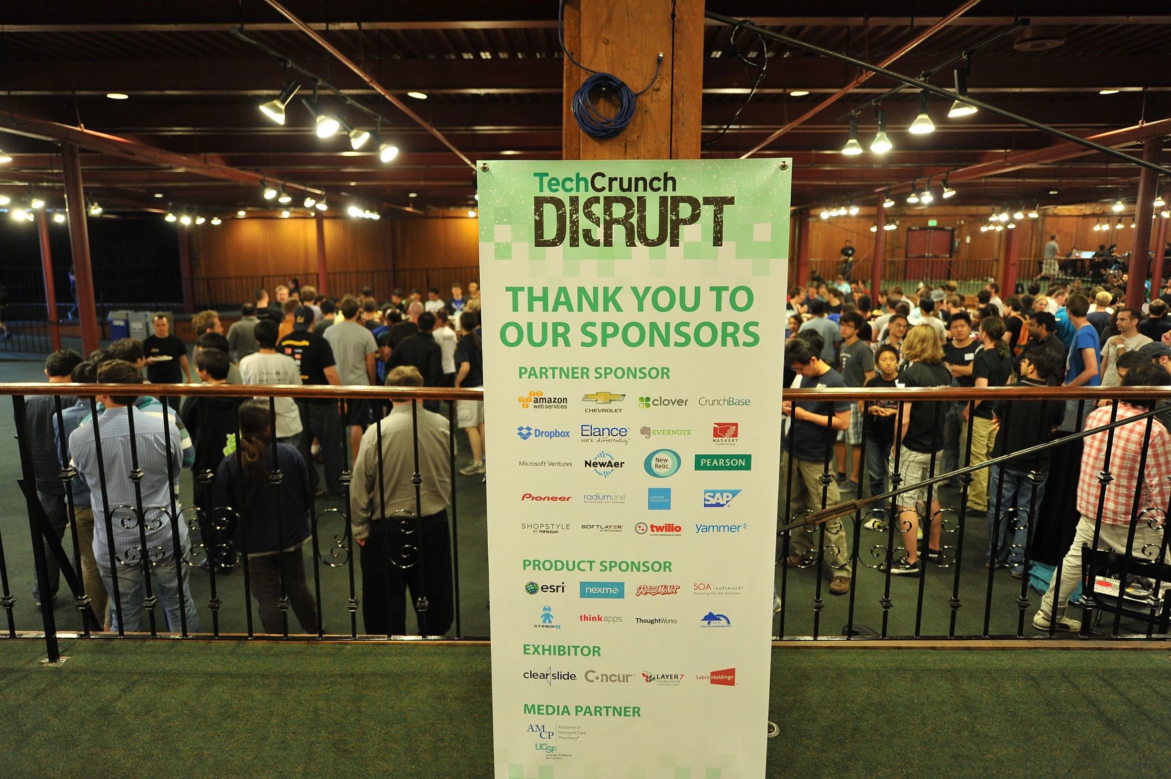 people standing in a room with green walls with an information board for the event