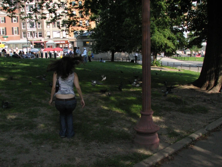 woman walking toward an area with many pigeons in it