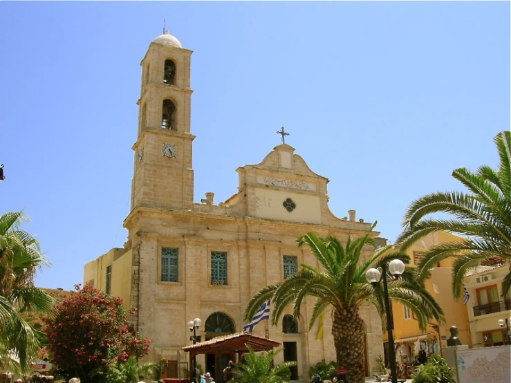 a church with palm trees and two people sitting on benches