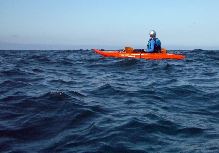 man in red boat in open ocean water