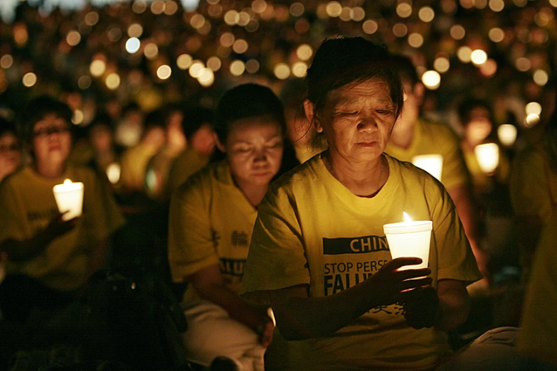 a young child sits next to a candlestick in a large candlelight procession