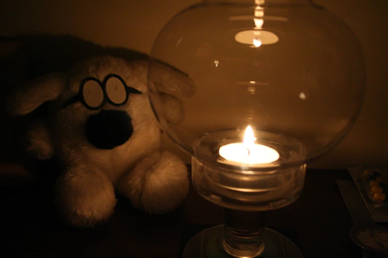 a stuffed animal near a glass candle holder