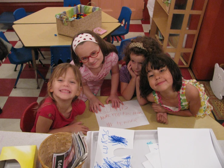 several children smile at the camera in an classroom