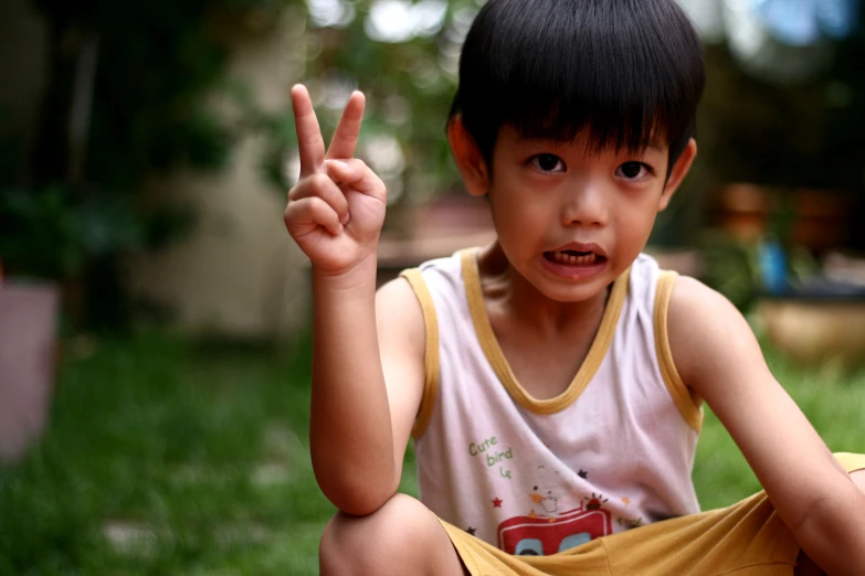 an asian  sitting outside showing the peace sign