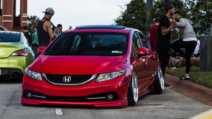 a red honda civic hatch is parked in front of other cars