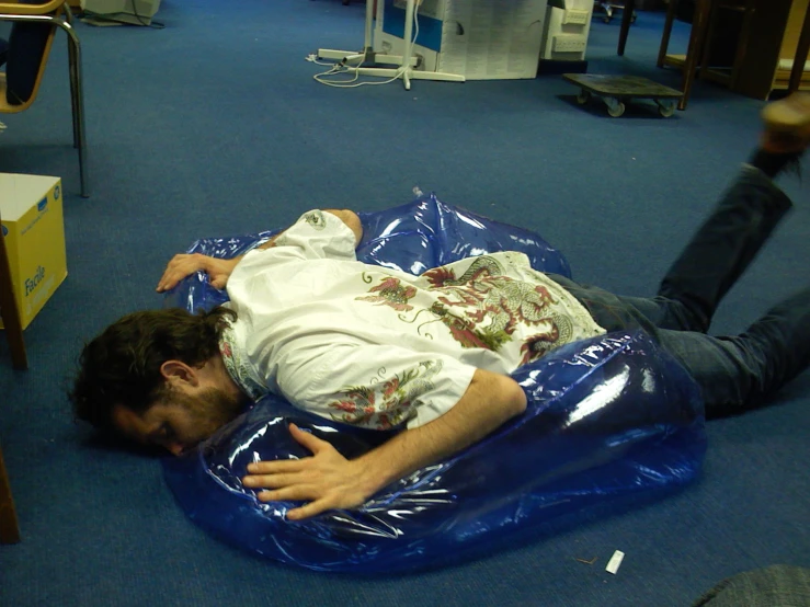 a man lays on the ground in an office setting