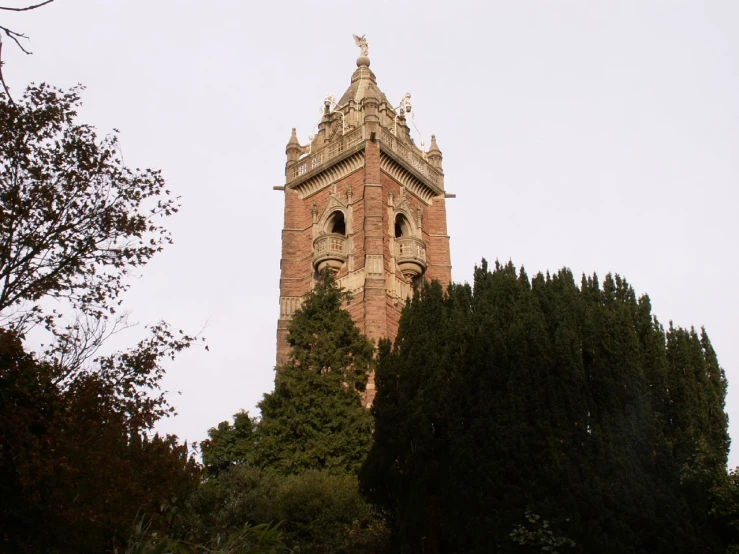 an old brick clock tower stands surrounded by trees