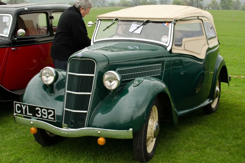 an old man looking at a car parked on a field