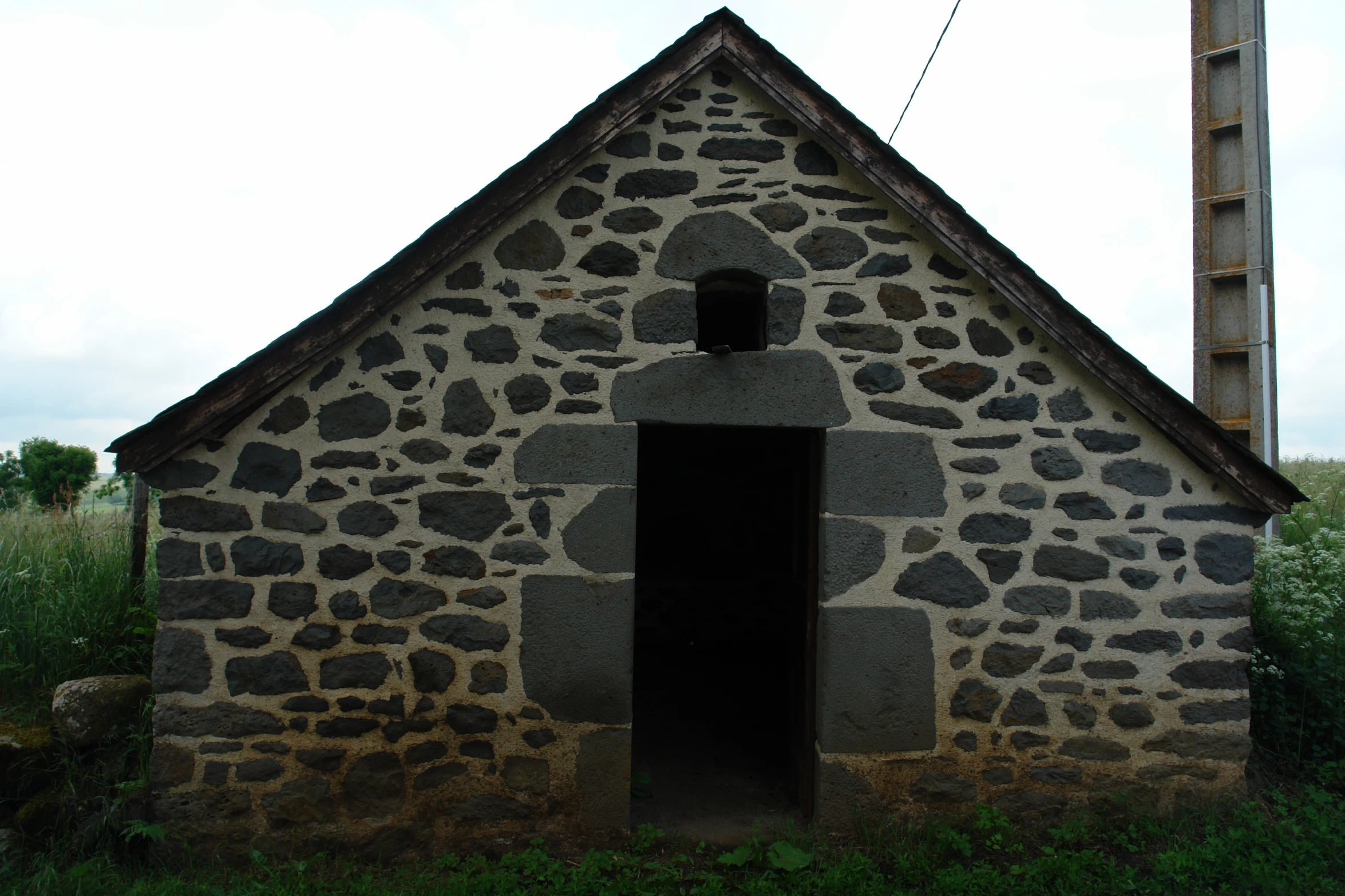 a building made out of stone and surrounded by lush green trees