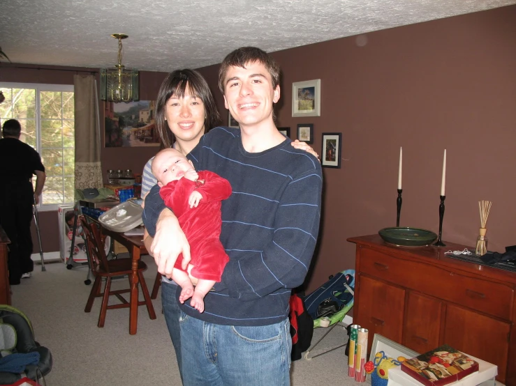 a woman holding her baby while standing next to a man