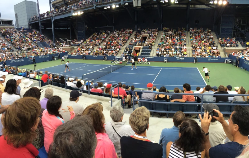 an outdoor tennis match that is being watched by people