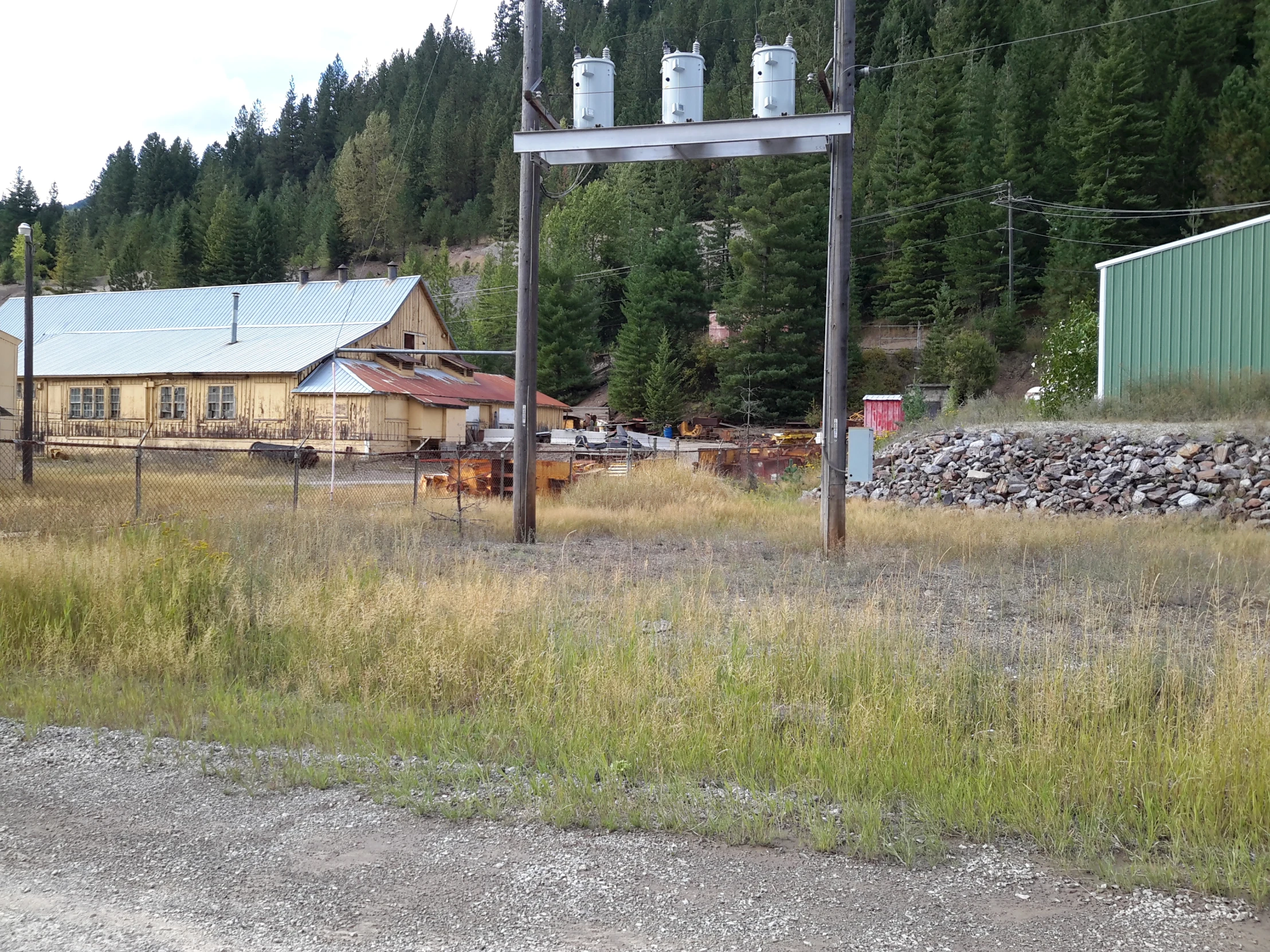 an old abandoned gas station with an empty field near the woods