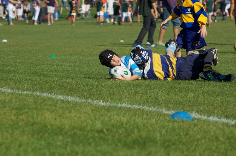 a young man lays on the grass while holding a ball
