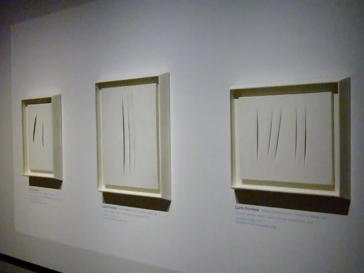 three small rectangular paintings are on display in a museum