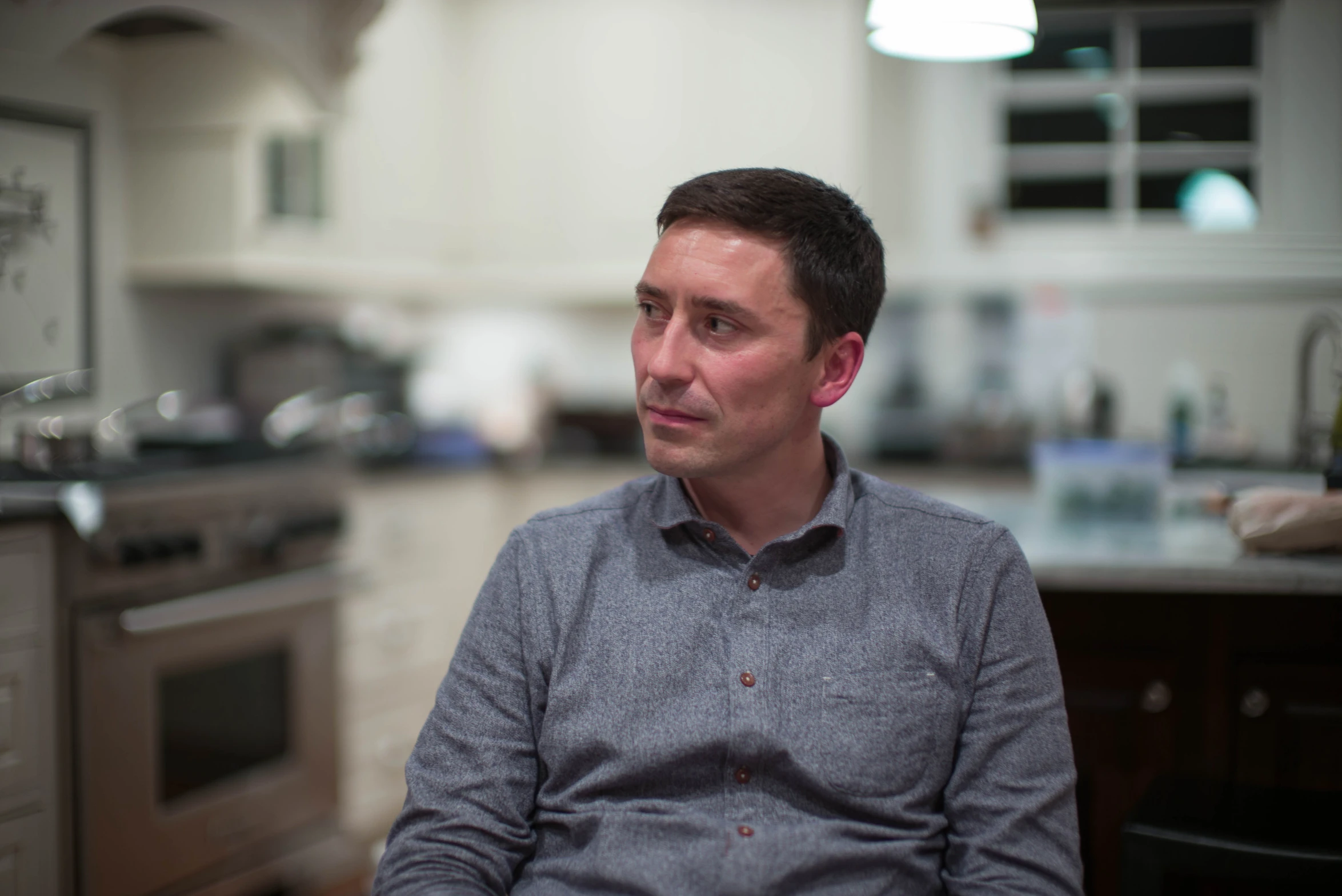 man sitting in a kitchen talking to someone