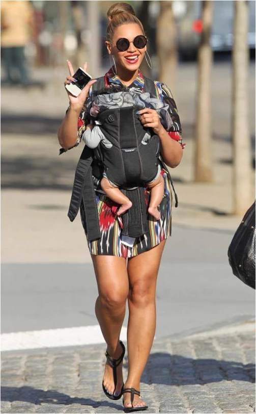 the mother carries her baby girl as she walks on a sidewalk