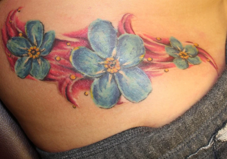 a woman is wearing a pink and blue tattoo with flowers on the side