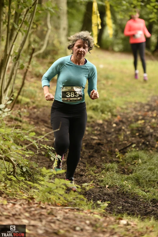 a woman running down a path in the woods