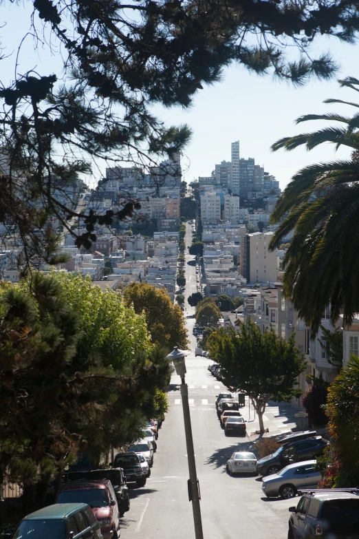 this view down a steeply sloped street has cars parked along it