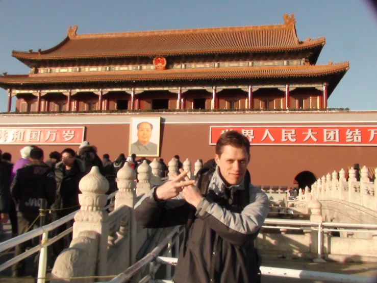 man making hand gestures in front of oriental building