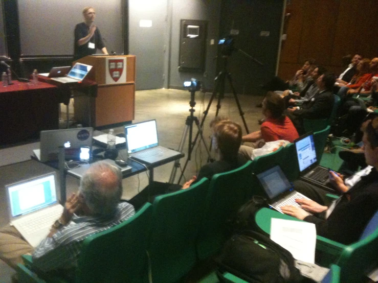 an audience in seats watching a lecture in front of a podium