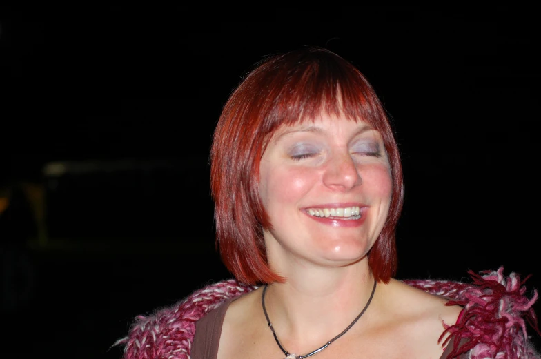 woman with red hair smiling while looking at the camera