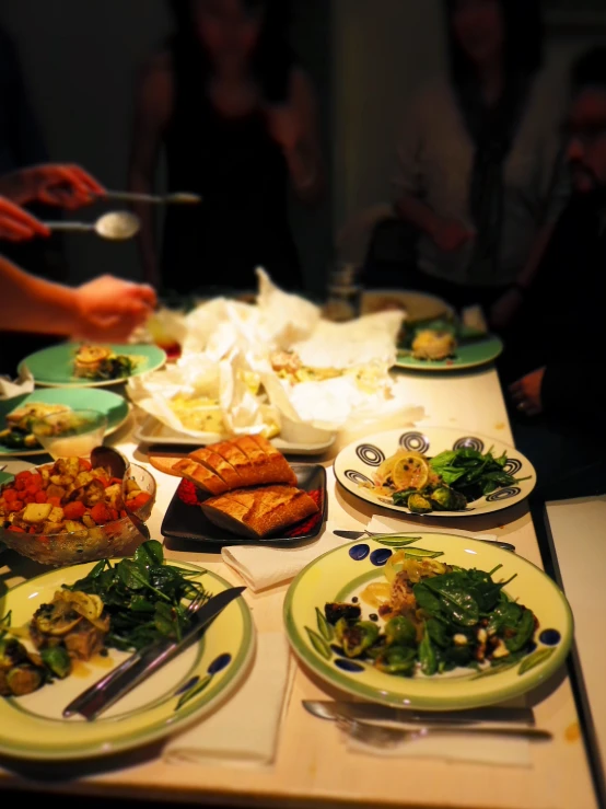 several plates of food at a table with people sitting around