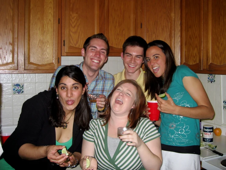 four friends taking selfies together in a kitchen