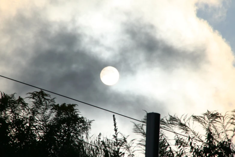 the sun peeking over a hill, from behind the clouds