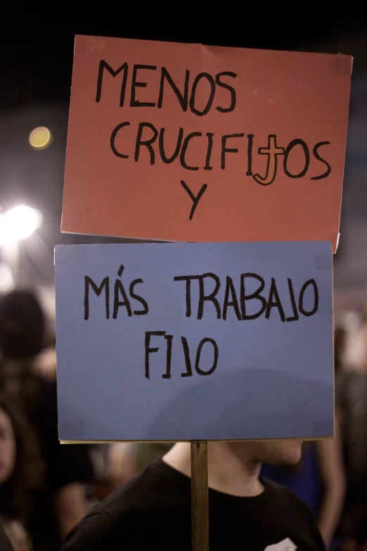 two signs with spanish words sitting on top of a pole