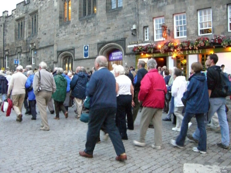 many people on the street in front of a stone building