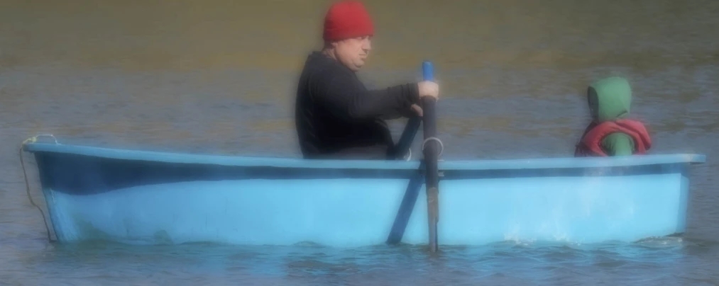 man in a boat is holding a pole and wearing a red hat