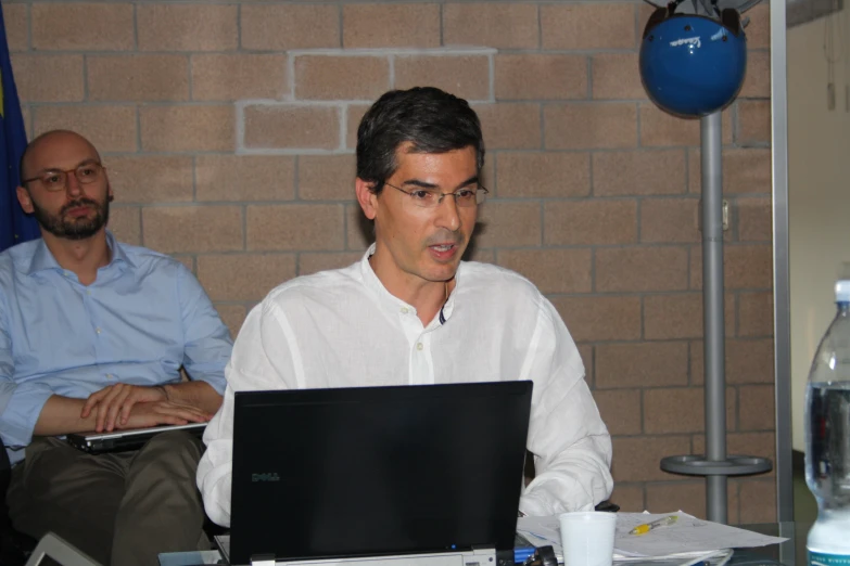 two men working at a laptop in an office setting