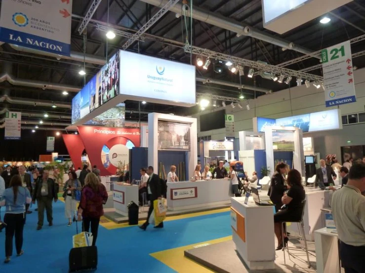 a crowd of people walking around a showroom at an exhibition