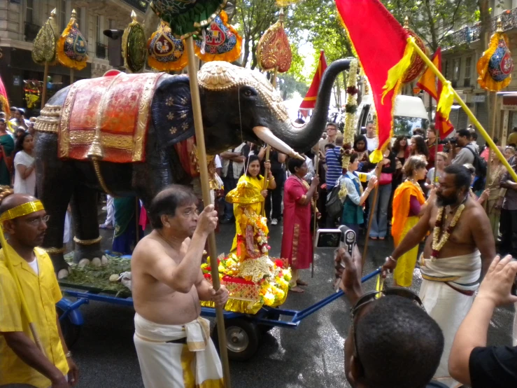 an elephant on a cart with a few men around it